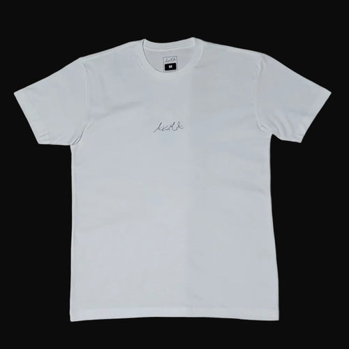 White long-sleeve shirt on a beige surface with shoes in the background