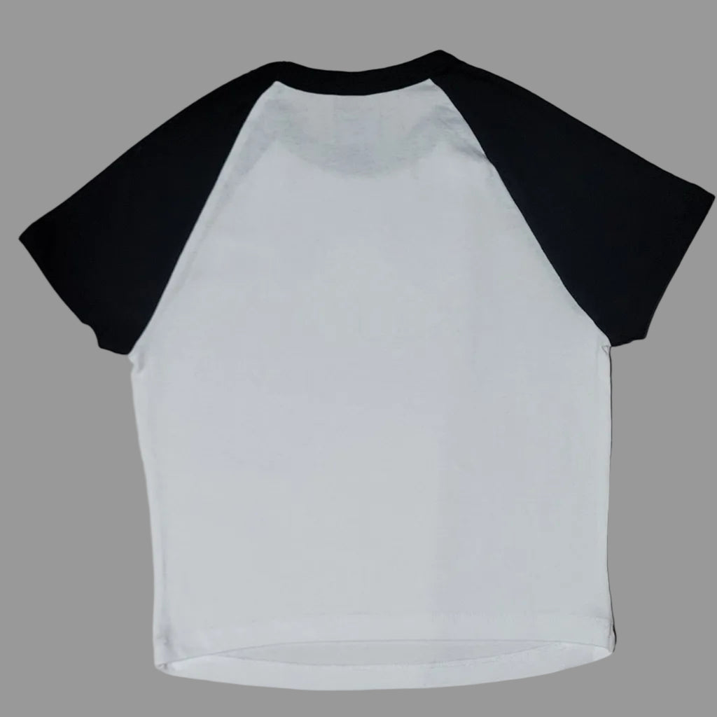 White long-sleeve shirt with black sleeves on a beige surface