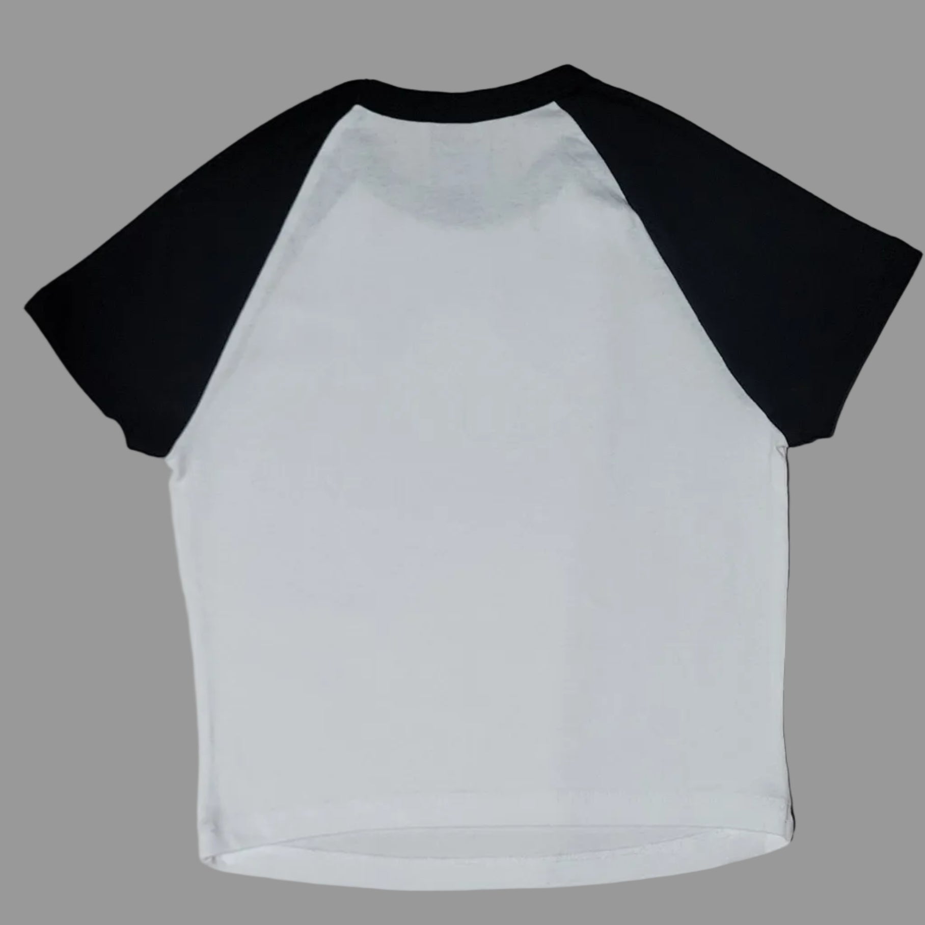 White long-sleeve shirt with black sleeves on a beige surface